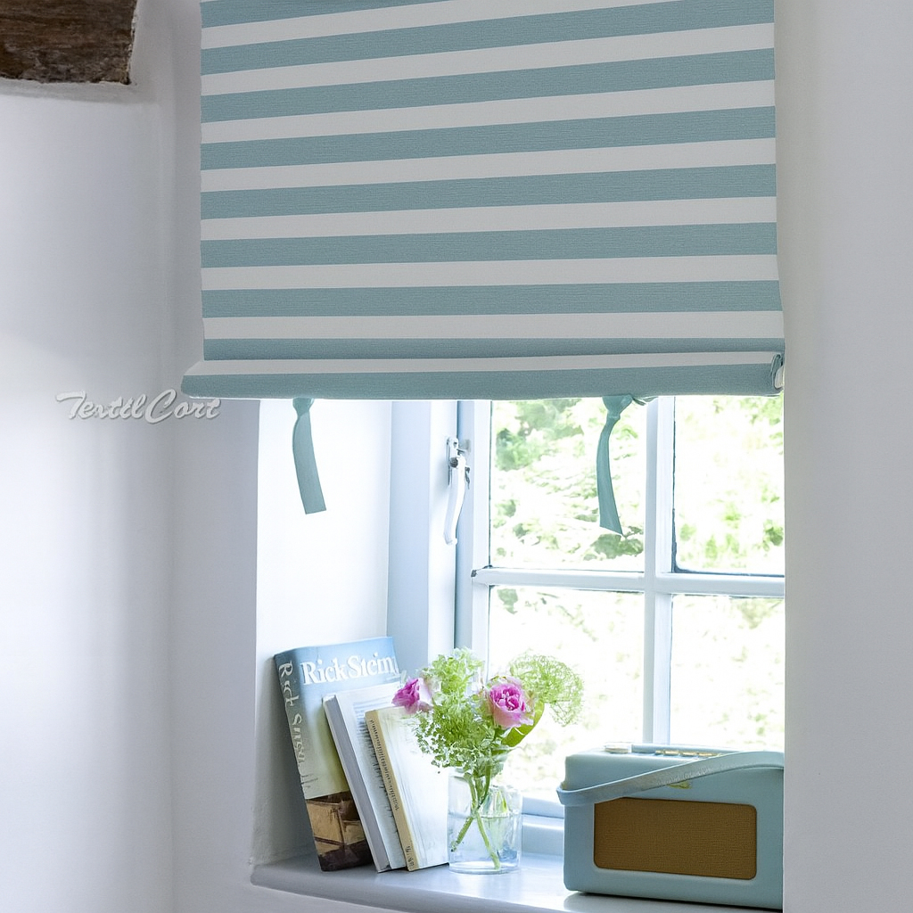 Detalle de estor a rayas azul pastel en ventana con libros y decoración vintage